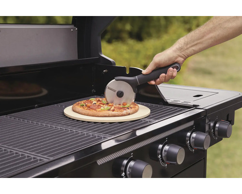 Person schneidet Pizza auf Grill mit Pizzastein und Pizzaschneider