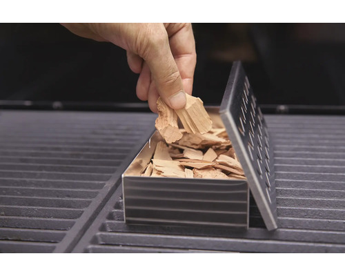 Remplissage d''une boîte à fumée avec des copeaux de bois sur un barbecue