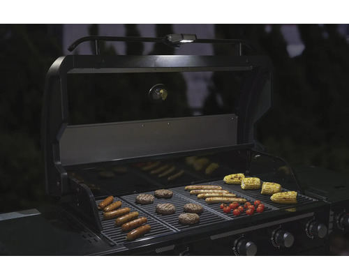 Barbecue avec saucisses, hamburgers, maïs et tomates sur la grille