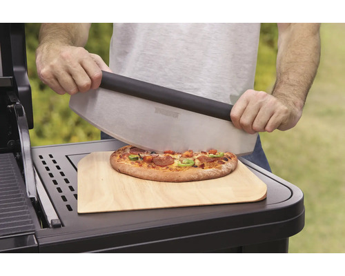 Eine Person schneidet Pizza mit einem Pizzaschneider auf einem Holzbrett.