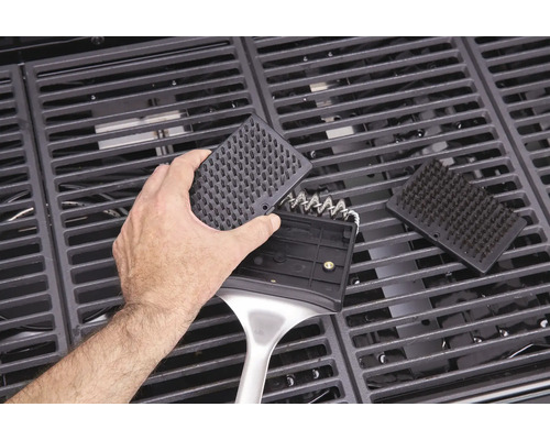 Person reinigt Grillrost mit Grillbürste