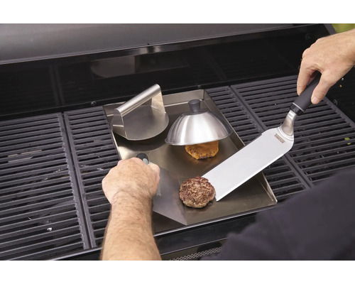 Préparation de hamburgers sur une plaque de cuisson avec presse à hamburger et spatule