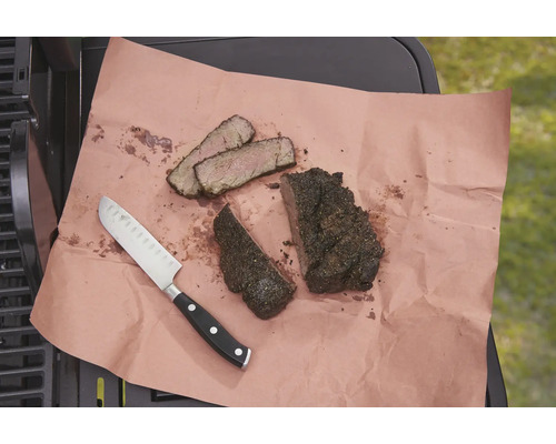 Auf einem Stück Papier liegen ein Messer und aufgeschnittenes Fleisch.