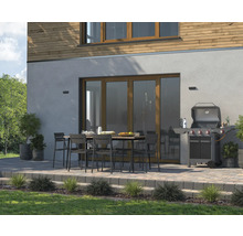 Terrasse mit Gartentisch, Stühlen und Grill vor einem Haus.