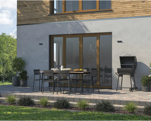 Scène d''extérieur avec barbecue, table de jardin et chaises sur une terrasse devant une maison