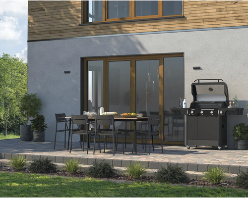 Terrasse avec table à manger, chaises et barbecue à gaz devant une maison.