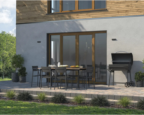 Espace extérieur avec table de jardin, chaises et barbecue sur une terrasse pavée