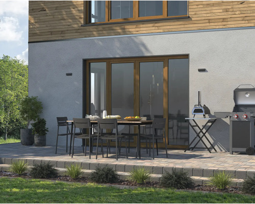 Terrasse mit Esstisch, Stühlen, Grill und Pizzaofen vor einem Haus