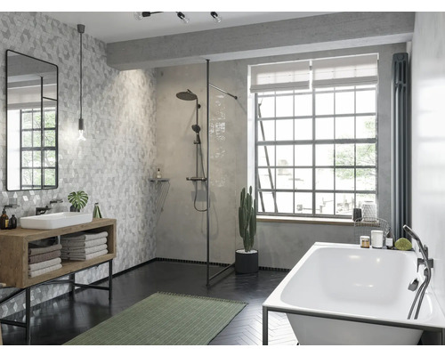 Salle de bains avec douche, baignoire, lavabo, miroir et carrelage à motifs géométriques.