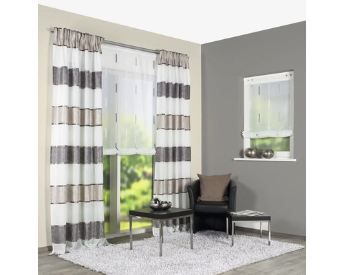 Salon avec rideaux rayés, store enrouleur et fauteuil sur un tapis