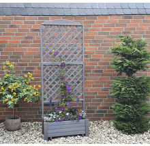 Jardinière en bois avec treillis devant un mur de briques dans le jardin.