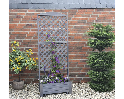 Jardinière en bois avec treillis devant un mur de briques dans le jardin.