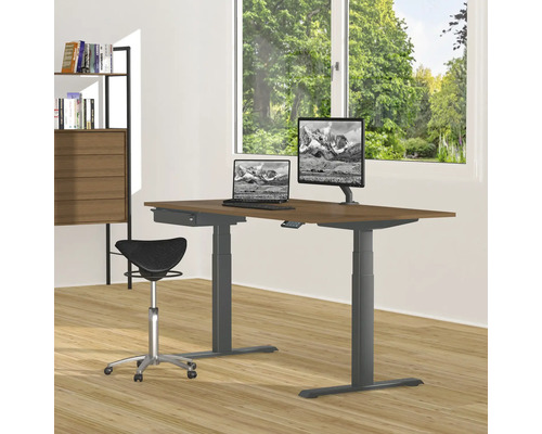 Bureau réglable en hauteur avec ordinateur portable, moniteur et chaise de bureau dans une pièce lumineuse.