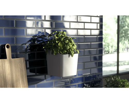 Mur avec carreaux rectangulaires, pot d''herbes aromatiques et planche à découper