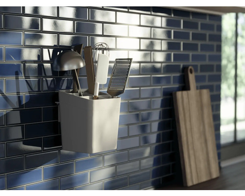 Scène de cuisine avec carrelage bleu foncé, porte-ustensiles de cuisine et planche à découper