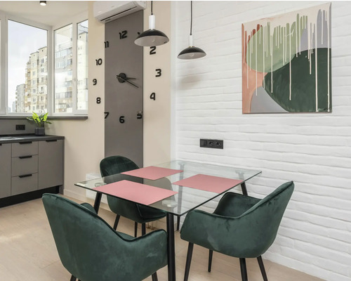 Salle à manger avec table en verre, chaises vertes et décoration murale