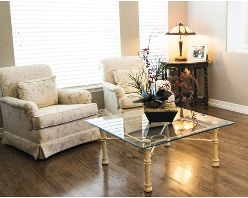Salon avec deux fauteuils, une table basse avec un plateau en verre et une lampe de table