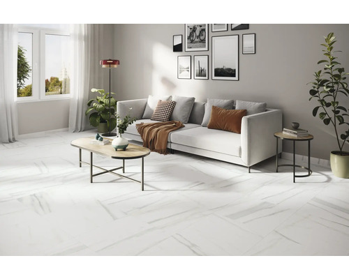 Séjour lumineux avec canapé blanc, table basse et revêtement de sol blanc aspect marbre.