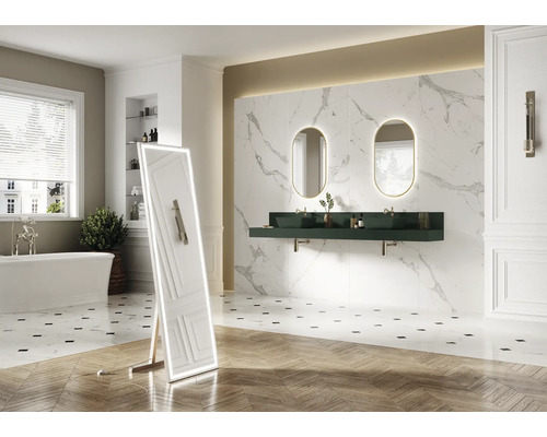 Salle de bains avec baignoire, miroir, lavabo, miroirs ovales avec éclairage et carrelage mural imitation marbre