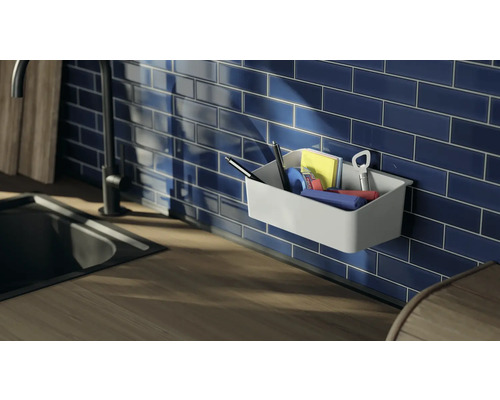 Panier mural avec articles de bureau devant un mur carrelé bleu dans la cuisine