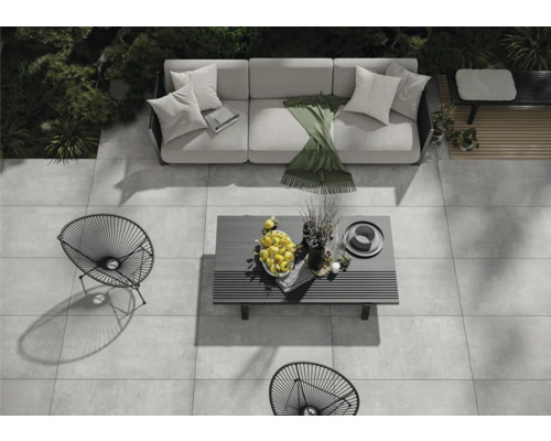 Ensemble de meubles de jardin sur une terrasse en pierre avec canapé, table et chaises en métal.