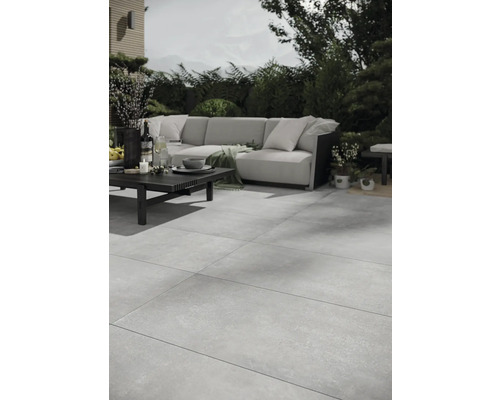 Terrasse avec carrelage en grès cérame de grand format, ensemble de canapés et table à l'extérieur.