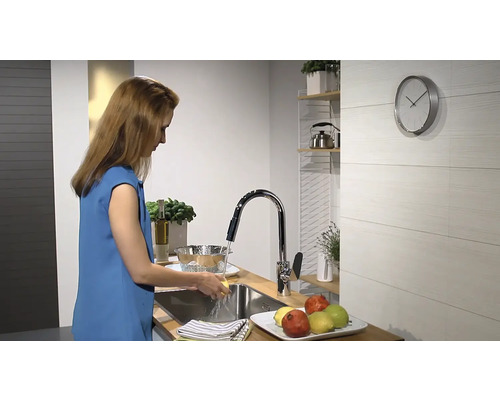 Frau wäscht in einer modernen Küche Gemüse unter einem Wasserhahn