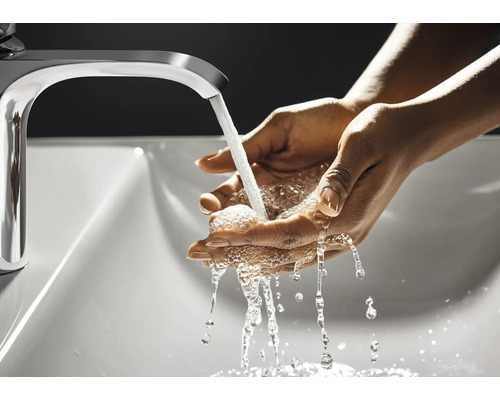 Eine Person wäscht sich die Hände unter einem Wasserhahn in einem Waschbecken
