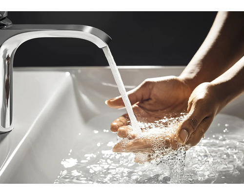 Eine Person wäscht sich die Hände unter einem Wasserhahn in einem Waschbecken.