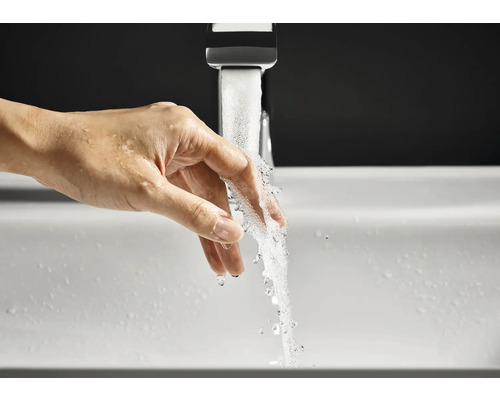 Eine Hand wird unter einen laufenden Wasserhahn in einem Waschbecken gehalten.