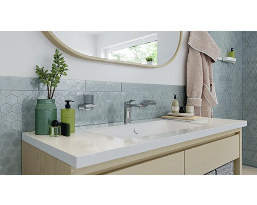 Badezimmerwaschtisch mit Armatur, Spiegel und Accessoires für eine moderne Badgestaltung.