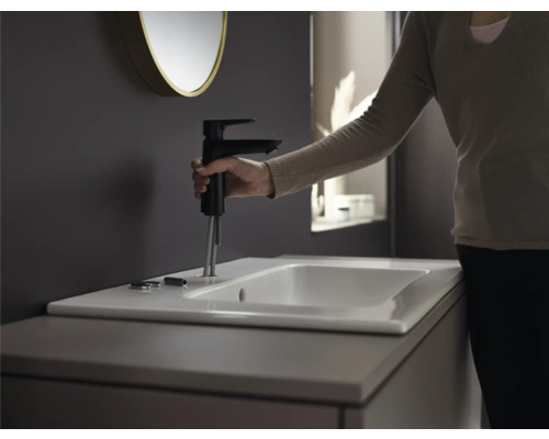 Installation eines schwarzen Wasserhahns an einem weißen Waschbecken im Badezimmer.