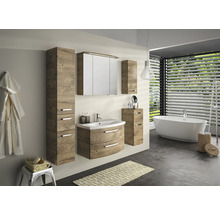 Salle de bains avec lavabo, armoire de toilette et armoire haute à l''aspect bois, ainsi que baignoire et porte-serviettes.