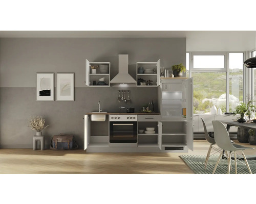 Komplette Küchenzeile mit Spüle, Herd, Dunstabzugshaube, Kühlschrank und Oberschränken in einem hellen und organisierten Raum.