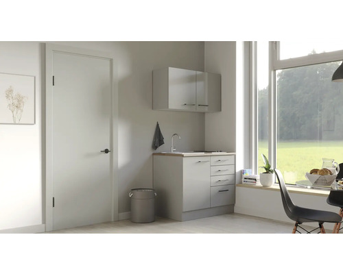 Buanderie lumineuse avec lavabo, meuble bas et meuble haut sous une grande fenêtre.