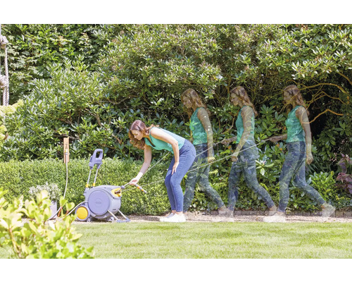 Une femme utilise un coffre à tuyau dans le jardin pour arroser les plantes.