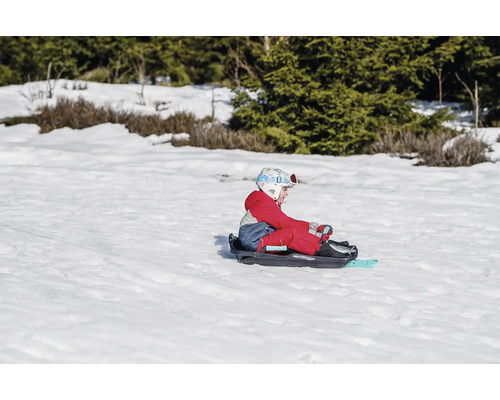 Enfant assis sur une luge dans la neige