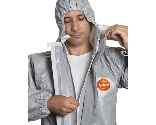 Un homme ferme une combinaison de protection grise avec capuche et fermeture éclair