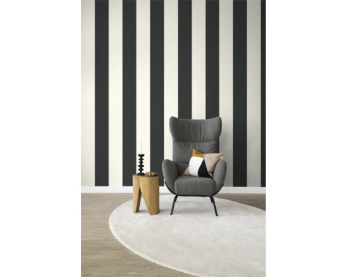 Wohnzimmer mit gestreifter Tapete, Sessel und rundem Teppich