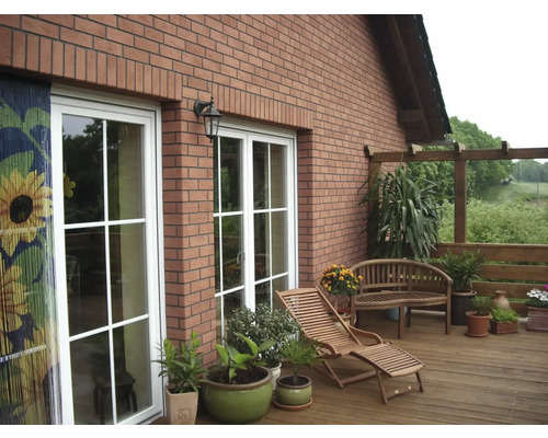 Terrasse mit Holzdeck, Gartenmöbeln, Pflanzen und Hausfassade aus Ziegeln