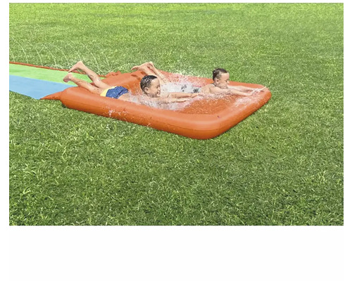 Deux enfants jouent sur un toboggan aquatique gonflable dans le jardin.