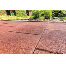 Gros plan de dalles de terrasse en caoutchouc rouge dans le jardin.