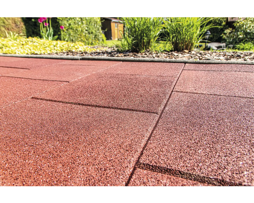 Gros plan de dalles de terrasse en caoutchouc rouge dans le jardin.