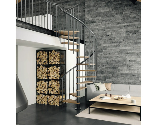 Wohnzimmer mit Wendeltreppe, Brennholzregal und grauer Steinwand