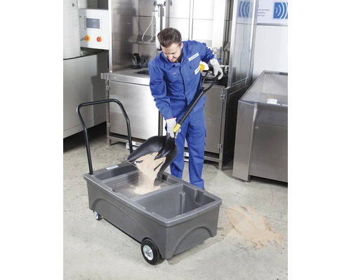 Mitarbeiter schaufelt Strahlmittel in einen mobilen Auffangbehälter.