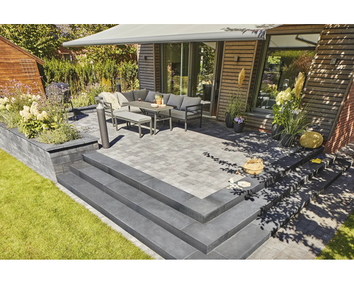 Terrasse mit Pflastersteinen, Stufen, Gartenmöbeln und Markise