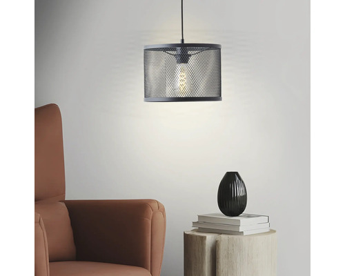 Hängelampe mit Lampenschirm aus Metallgeflecht über einem Beistelltisch und einem Sessel