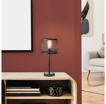 Lampe de table noire avec abat-jour en grillage métallique sur une table en bois.