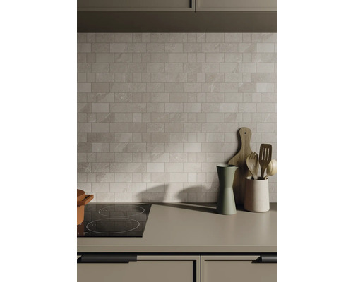 Küchenszene mit Fliesenwand, Kochfeld und Küchenutensilien auf der Arbeitsplatte.