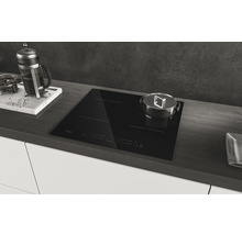 Plaque à induction noire dans une cuisine moderne avec casserole et cafetière